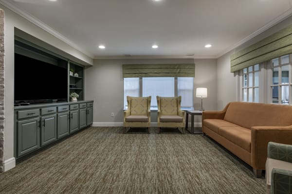 A cozy living room with a sofa, chairs, and a carpeted floor.