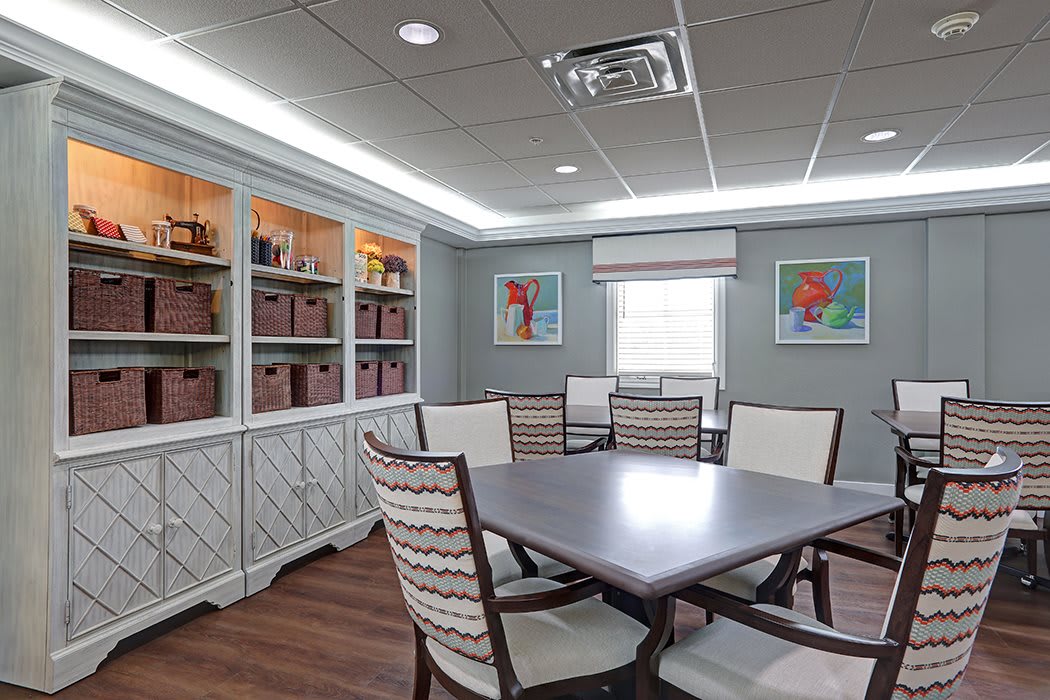 A well-lit conference room with a central table, chairs, and bookshelves lining the walls.