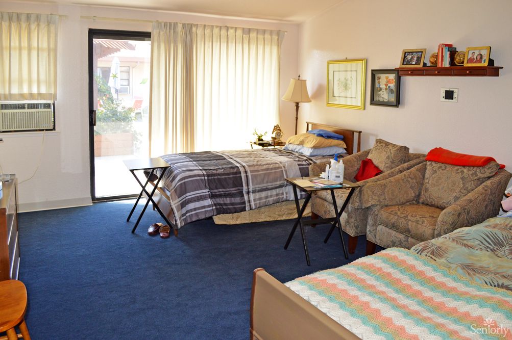 A cozy bedroom with two beds, a sofa, and a small table by the window.
