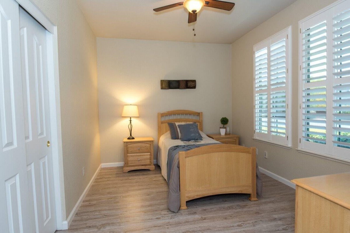 A minimalist bedroom with a single bed, nightstand, and lamp by the window.