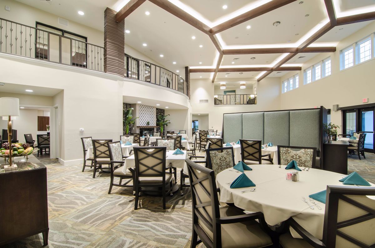 A modern indoor dining area with neatly arranged tables and chairs, featuring contemporary lighting and decor.