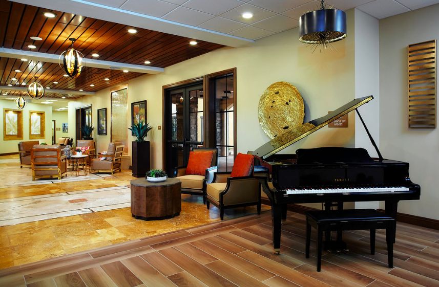 A spacious and elegantly designed living room featuring a grand piano, wooden flooring, and stylish seating.
