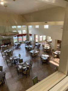 An empty dining area with neatly arranged tables and chairs, featuring large windows and elegant lighting.