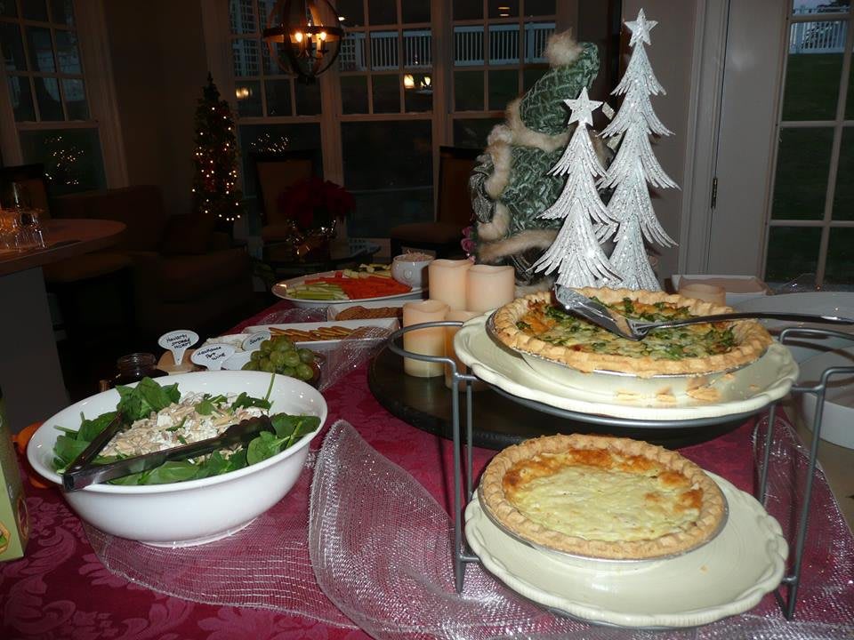 A festive holiday table set with quiches, salad, and Christmas decorations.