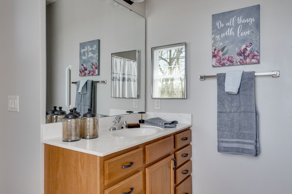 A neatly organized bathroom with a wooden cabinet, decorative wall art, and towels.