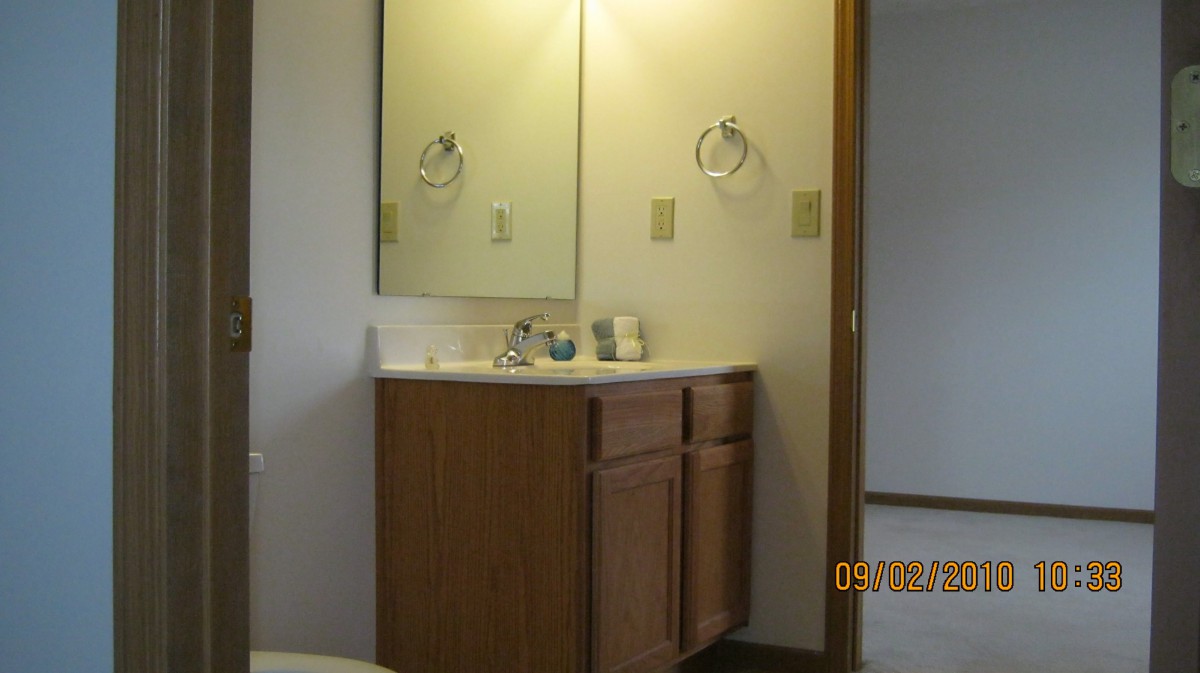 A bathroom with a wooden vanity and mirror above the sink.