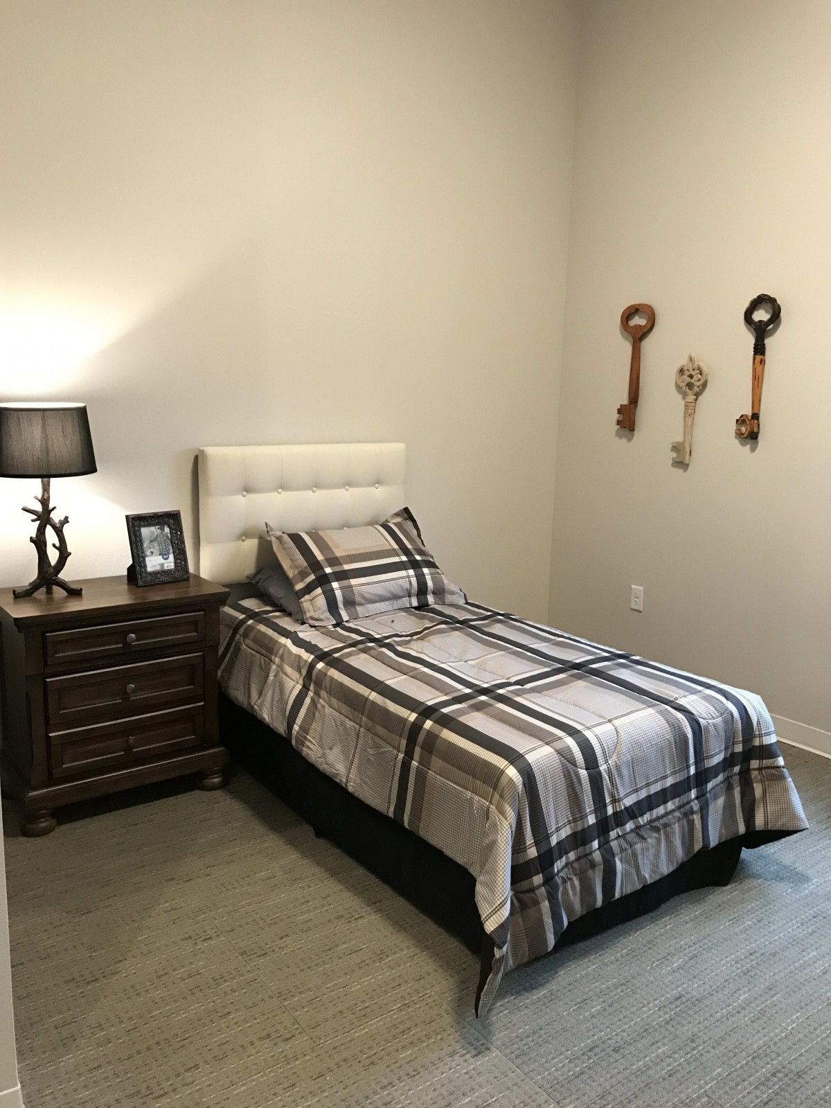 A minimalist bedroom with a single bed, nightstand, and decorative wall keys.
