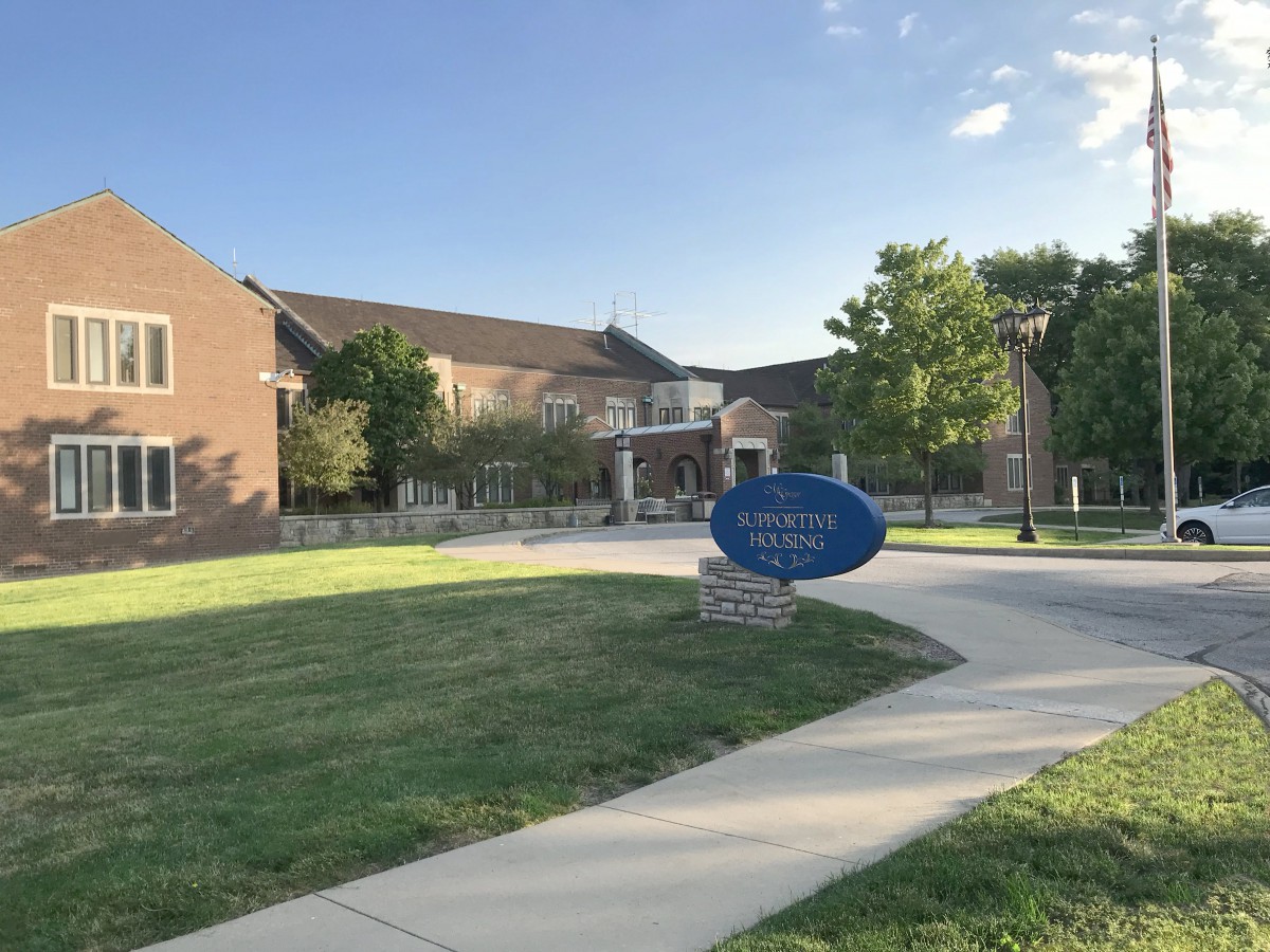 Entrance to St. Norbert College with a curved pathway and blue sign.