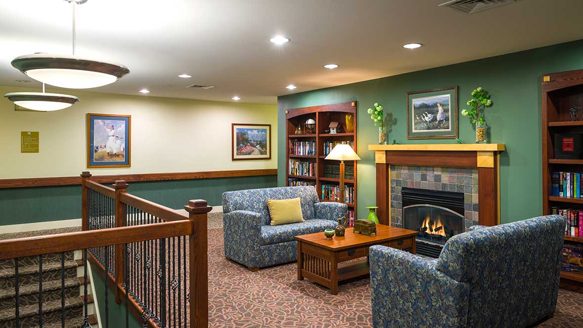 A cozy living room with a fireplace, comfortable seating, and a bookshelf.