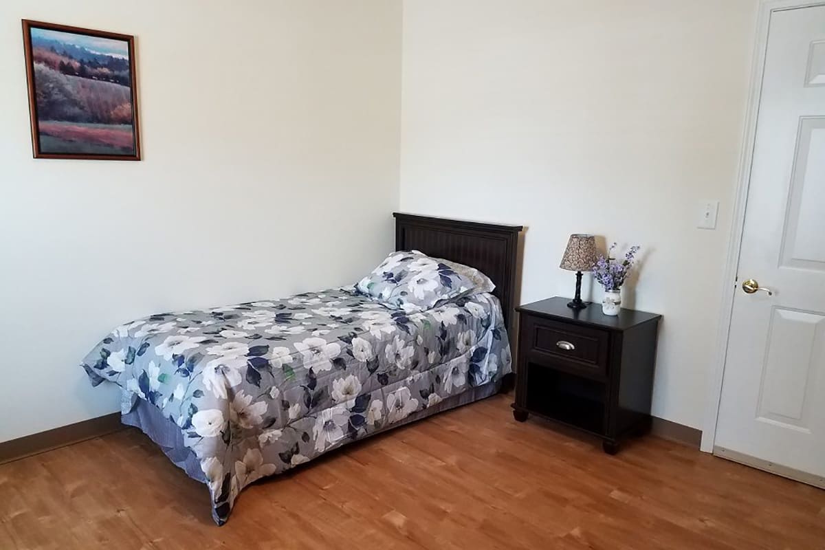 A simple bedroom setup with a single bed and nightstand.