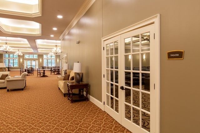 A well-lit hallway with French doors, a carpeted floor, and comfortable seating.