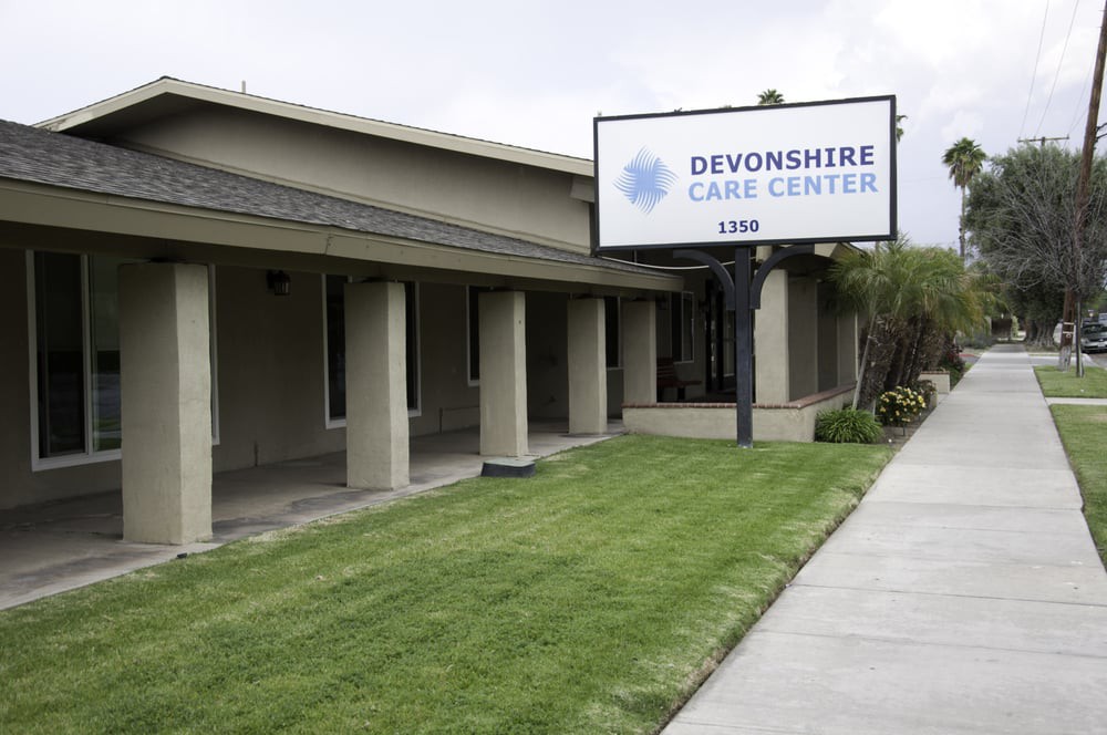 Exterior view of a care center with a visible sign and landscaped lawn.