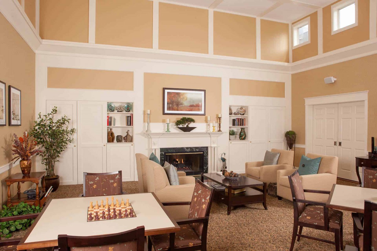 A cozy living room with a fireplace, comfortable seating, and a chessboard on the table.