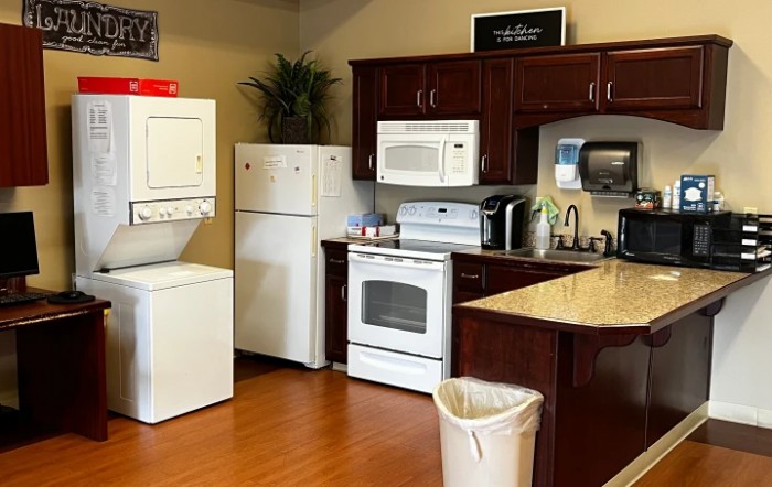 A cozy kitchen space featuring modern appliances, including a stacked washer and dryer set, a refrigerator, an oven, a microwave, and a sink.