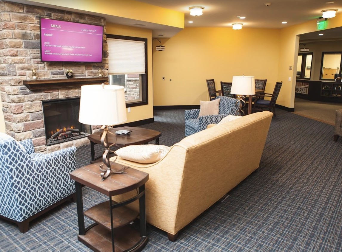 A cozy living room with a yellow couch, television, and fireplace, adjacent to a dining area.
