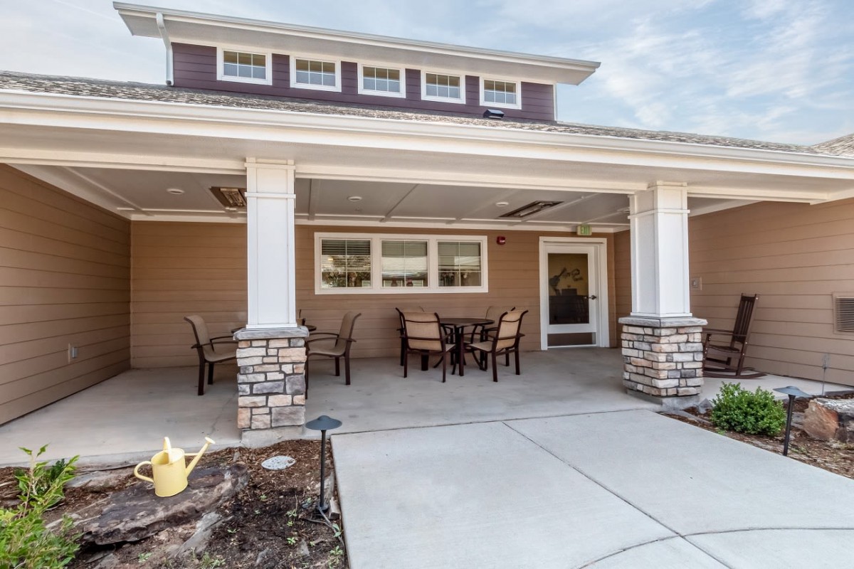 A covered patio area with outdoor seating and decorative columns.