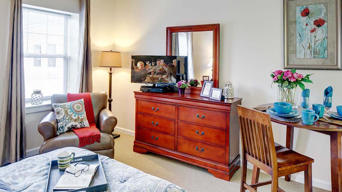 A cozy bedroom setup with a wooden dresser, mirror, and various decorative items.