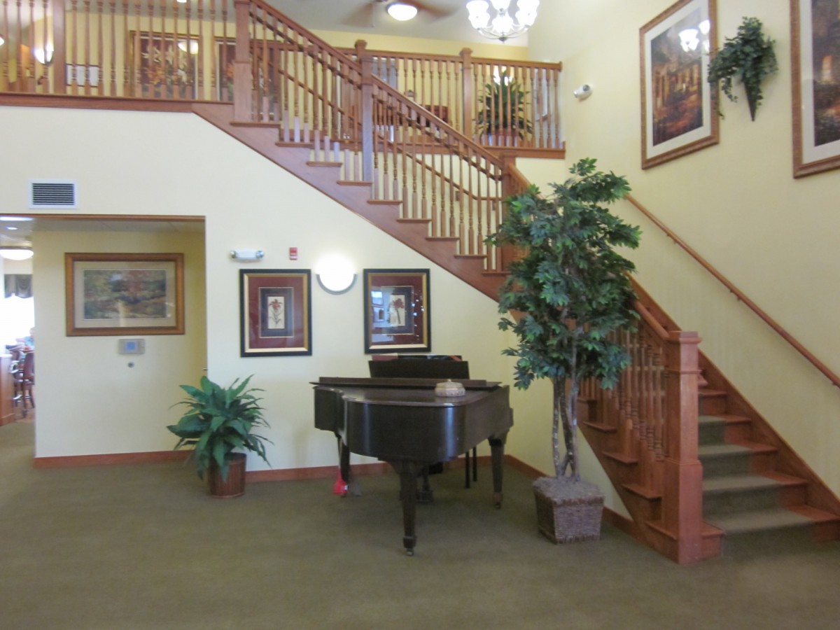 A cozy interior space featuring a grand piano and a wooden staircase.