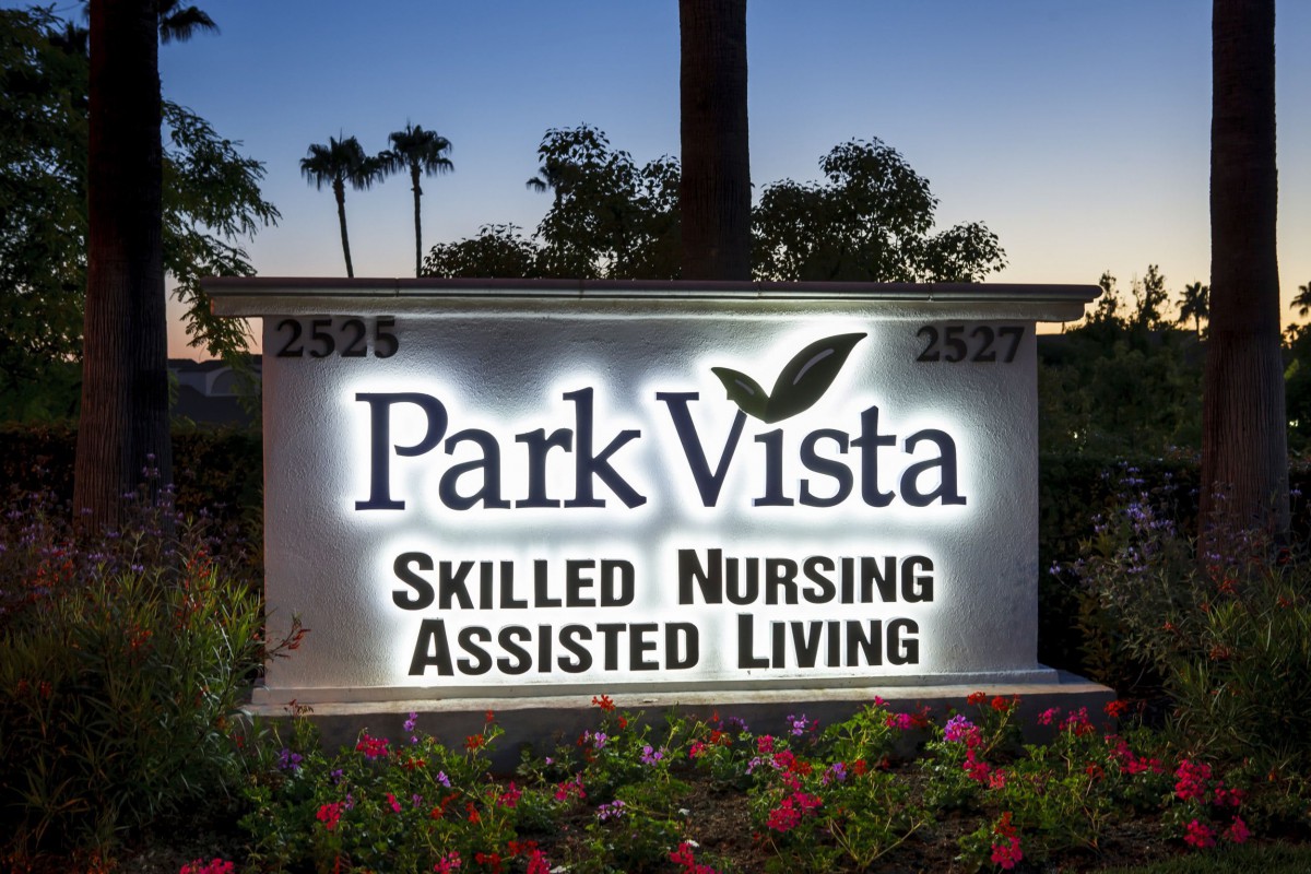 An illuminated sign for Park Vista Skilled Nursing and Assisted Living facility, set against an evening backdrop.