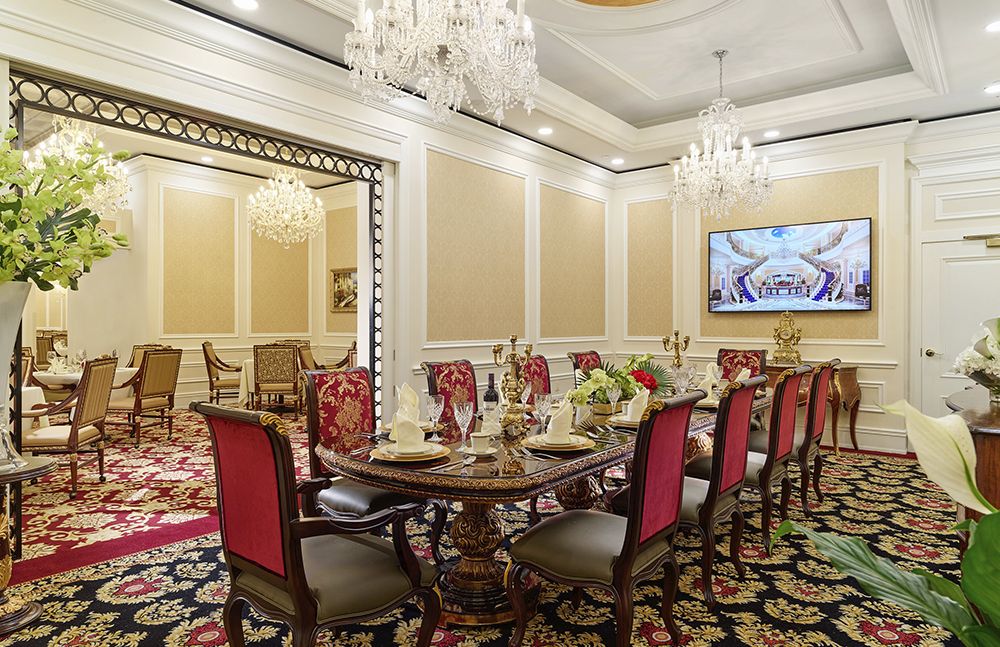 A luxurious dining room featuring elegant decor, a round table with red chairs, and chandeliers.