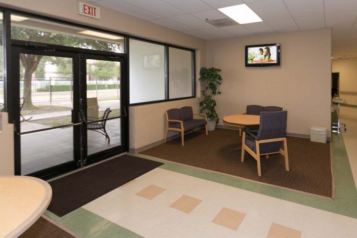 A small lobby area with chairs, a table, and a television near an entrance.