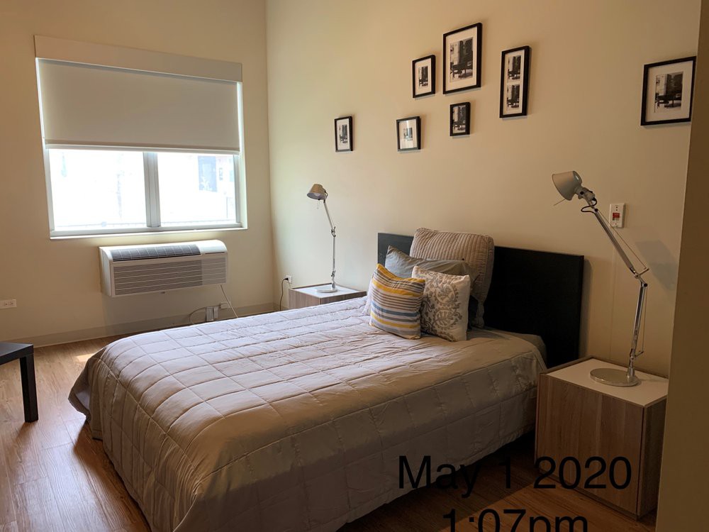 A neatly decorated bedroom with a bed, bedside tables, lamps, and framed pictures on the wall.
