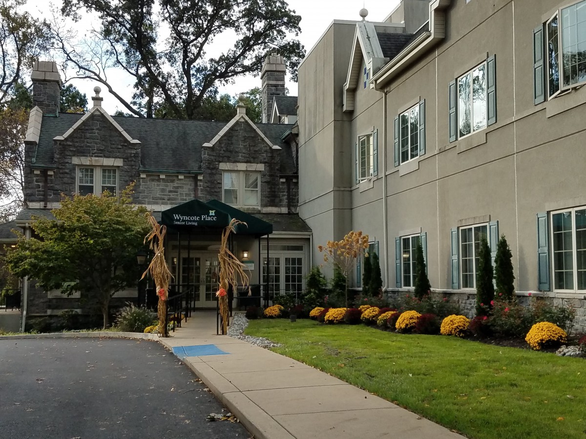 A building entrance with autumn decorations and well-maintained landscaping.
