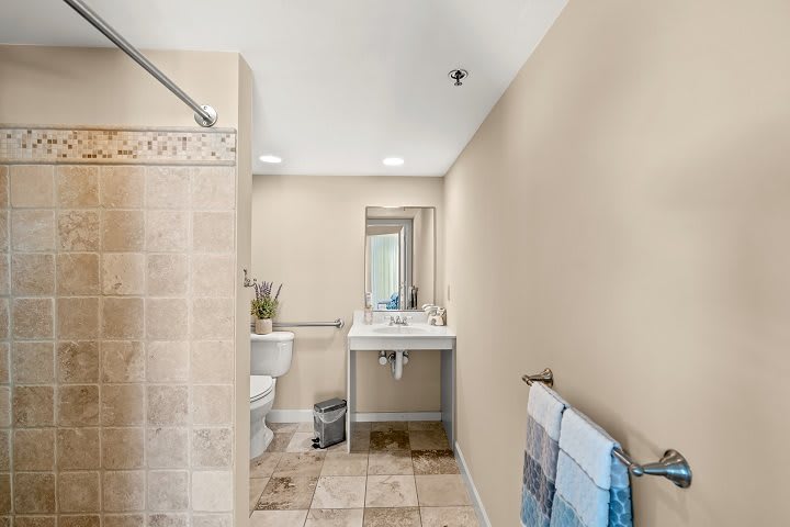 Modern bathroom with tiled floors, a shower area, and neatly arranged towels.