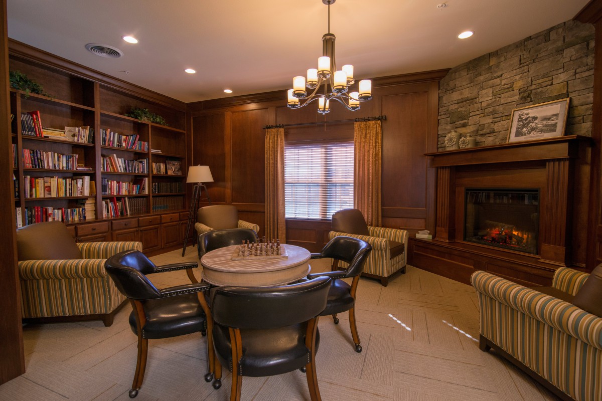 A cozy library room with a fireplace, bookshelves, and comfortable seating.