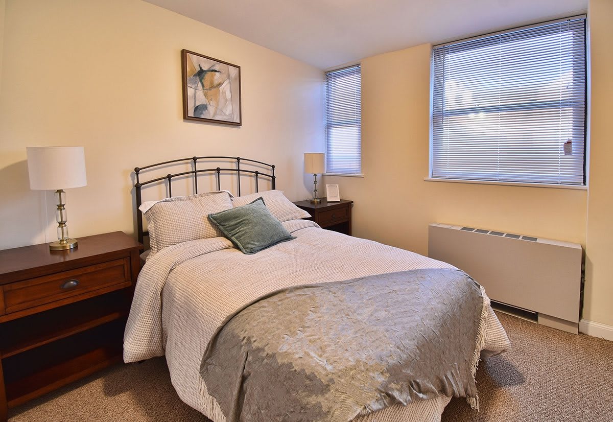 A cozy bedroom with a neatly made bed and soft lighting from the lamp.