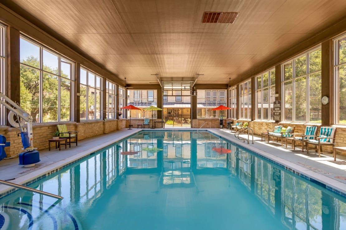 A tranquil indoor swimming pool with ample natural light filtering through large windows.