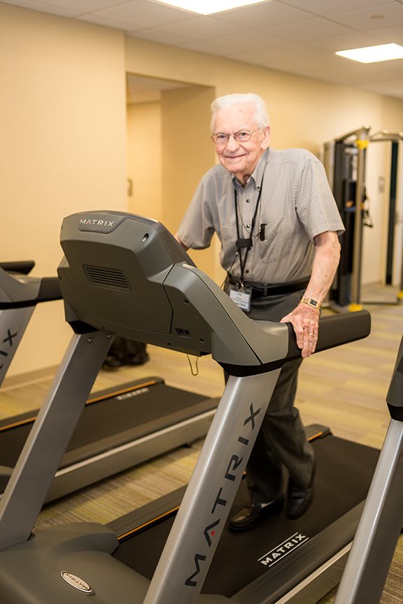 An elderly man using a treadmill in the gym.