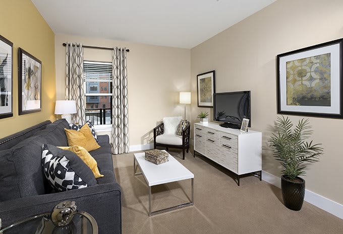A modern living room with neutral tones, featuring a sofa, coffee table, and TV stand.