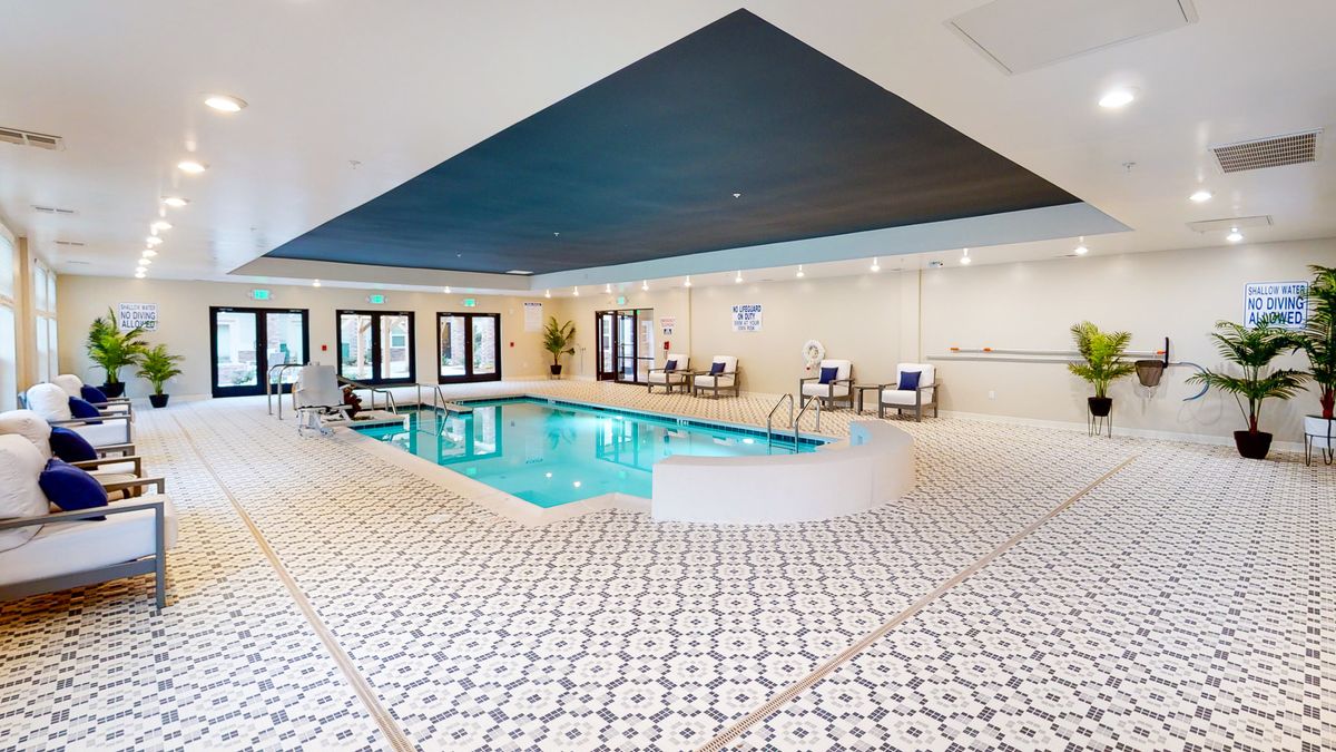 A modern indoor swimming pool with elegant tile flooring and a cozy relaxation area.