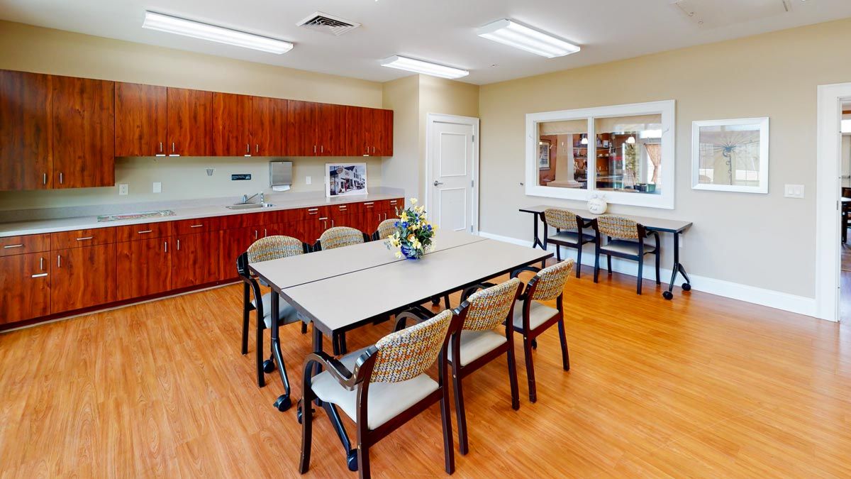 A well-lit meeting room with a conference table and chairs, complemented by wooden floors and cabinets.