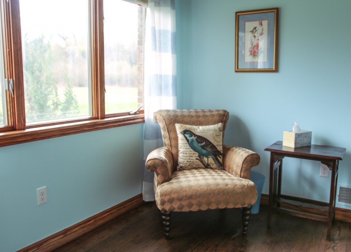 A cozy living room corner with an armchair, decorative pillow, and a side table.