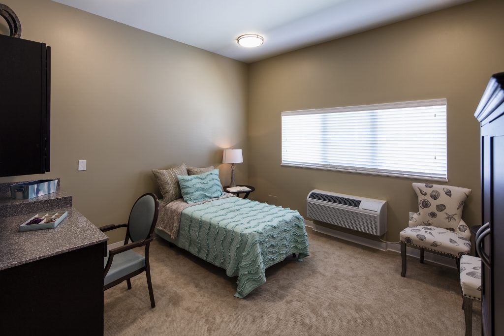 A minimalist bedroom with a single bed, bedside table, and chair.
