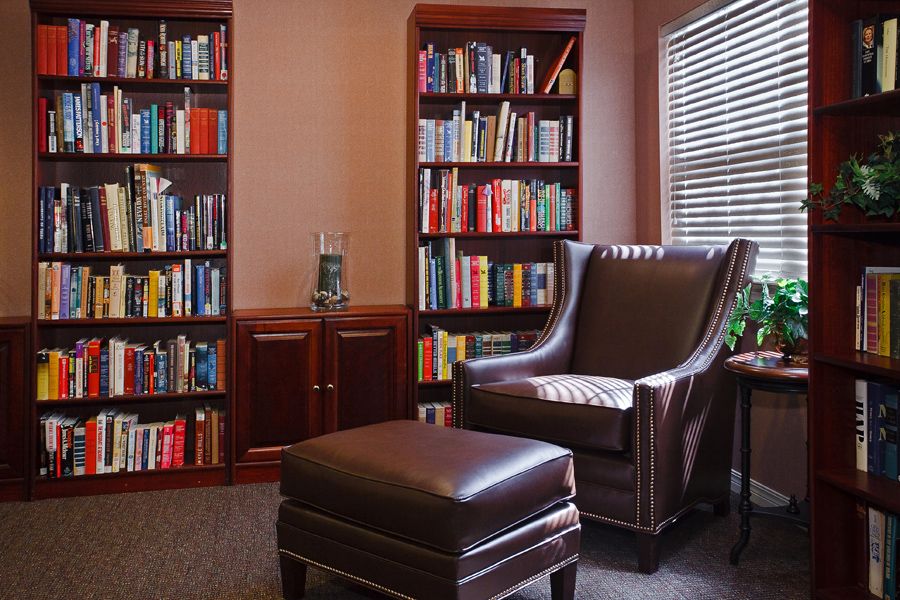 A cozy reading nook with a leather armchair, ottoman, and bookshelves filled with books.