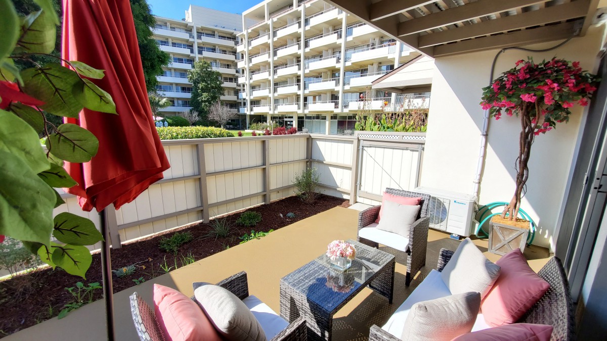 A cozy outdoor patio area with modern furniture, surrounded by apartment buildings.