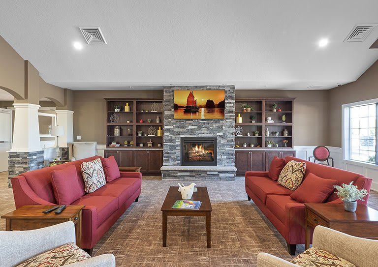 A cozy living room with red sofas and a fireplace surrounded by built-in shelves.