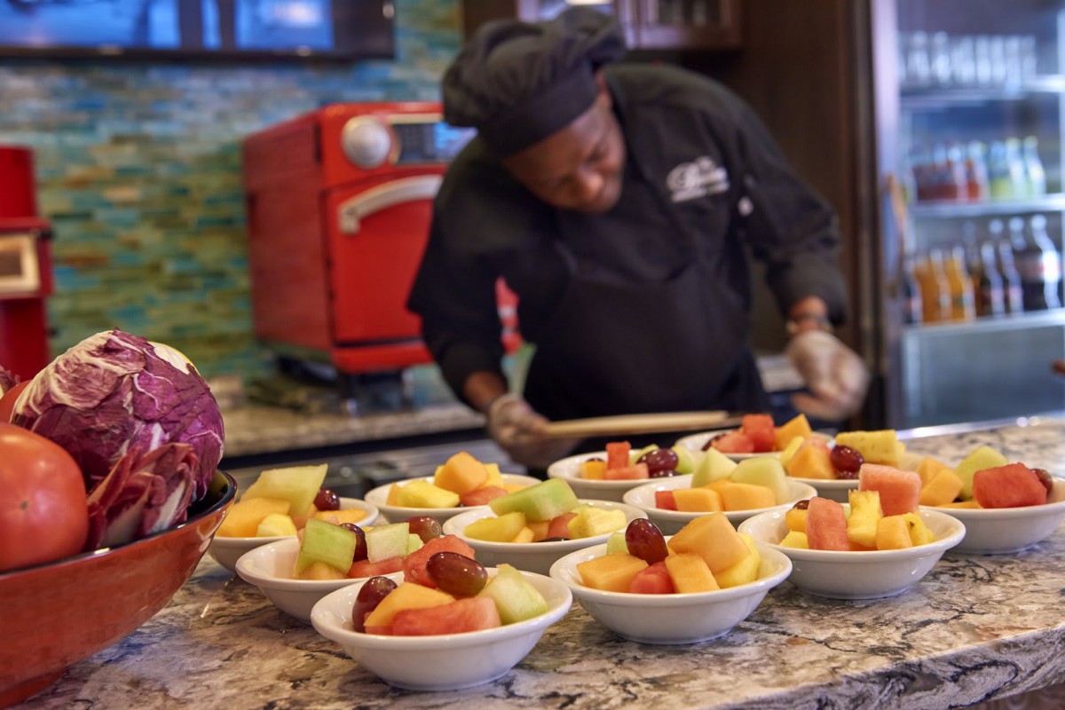 A chef prepares fruit bowls in the kitchen.