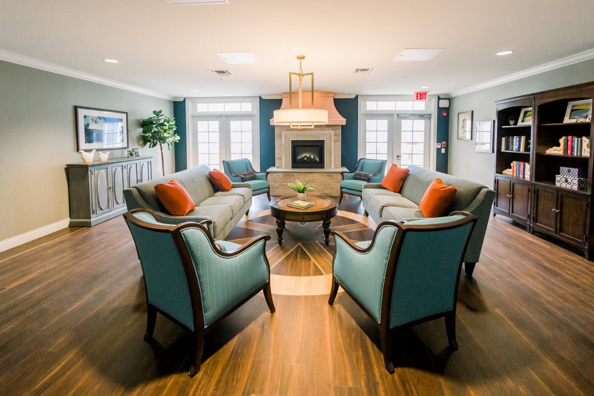 A cozy living room with a central fireplace, surrounded by elegant seating and accented with colorful cushions.