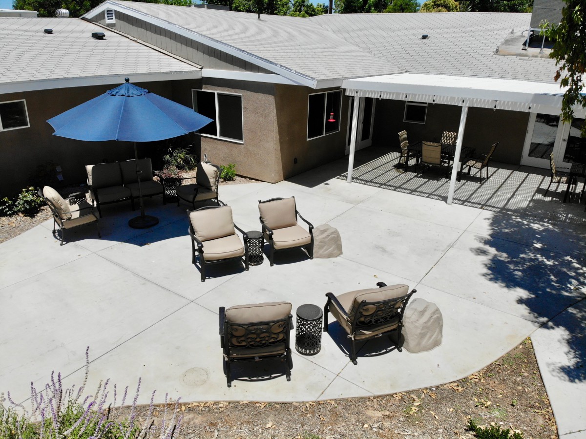 A well-furnished backyard patio with chairs and an umbrella providing shade.
