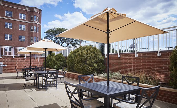 Outdoor patio area with tables, chairs, and umbrellas under a clear blue sky.