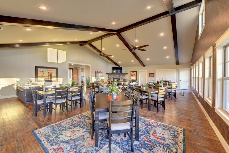 A spacious and elegantly designed dining area with tables and chairs, featuring exposed ceiling beams and tasteful decor.