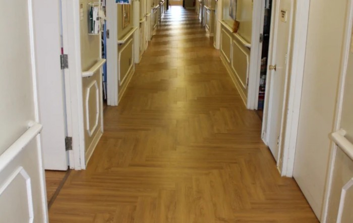 A long hallway with wooden flooring and multiple doors on each side.