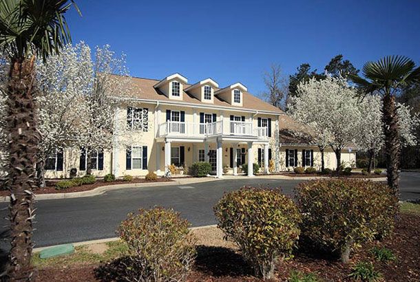 A large residential house with well-maintained landscaping and a driveway.
