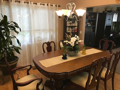 A cozy dining room featuring a wooden table, elegant chairs, and a floral centerpiece under a stylish light fixture.