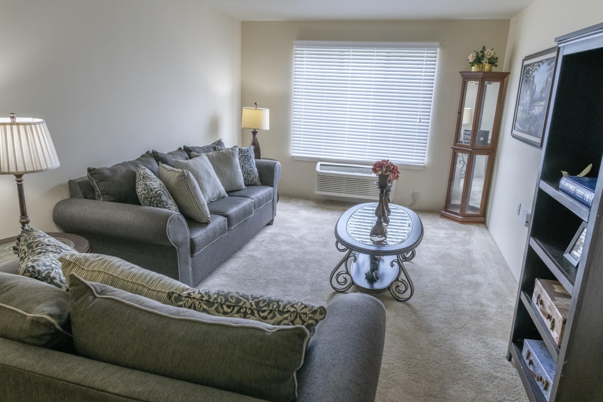 A cozy living room featuring a grey sofa set, coffee table, and soft lighting.