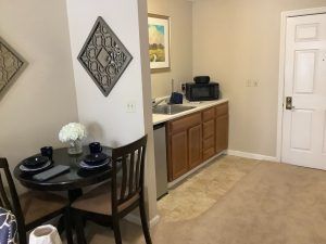 A cozy kitchenette and dining area in an apartment, featuring a small dining table set for two and compact kitchen appliances.